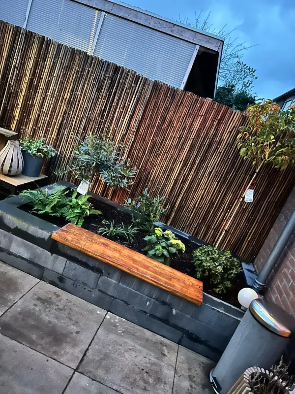 Bloembak met planten en bamboe schutting 