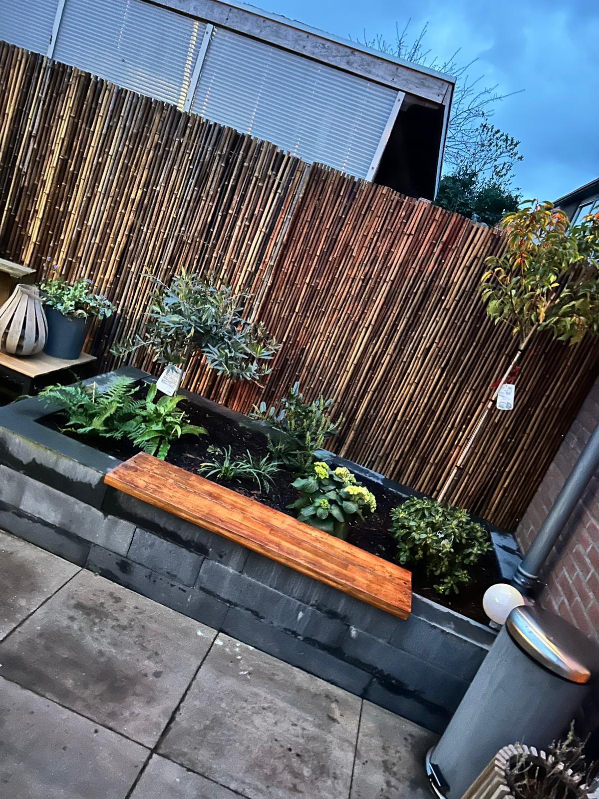 Bloembak met planten en bamboe schutting 